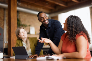 Happy African American businessman communicating with his female colleagues while working on a meeting in the office.